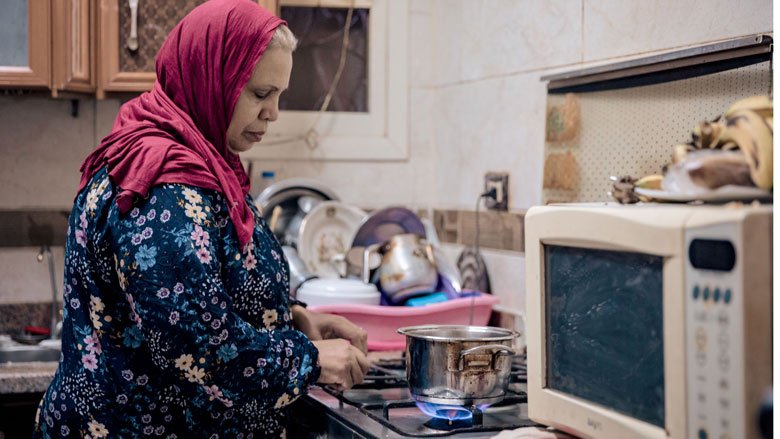 一位埃及妇女在厨房用天然气炉子做饭. 