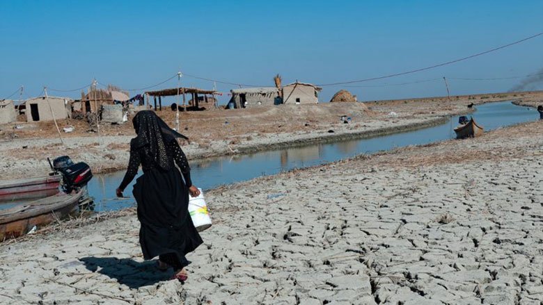在伊拉克南部中部沼泽地区，一名沼泽阿拉伯妇女正在干燥的湿地里取水.