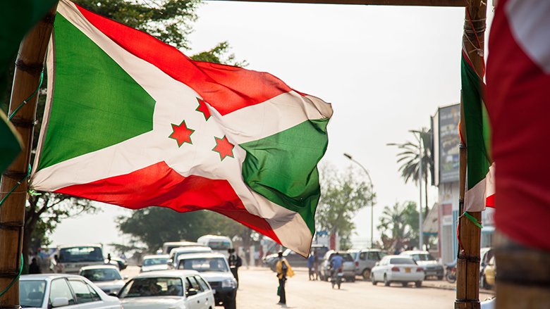 Burundi flag with cars in the background.