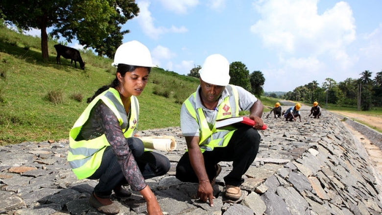 A female and a male construction worker checking quality and progress of a dam under construction in Sri Lanka.