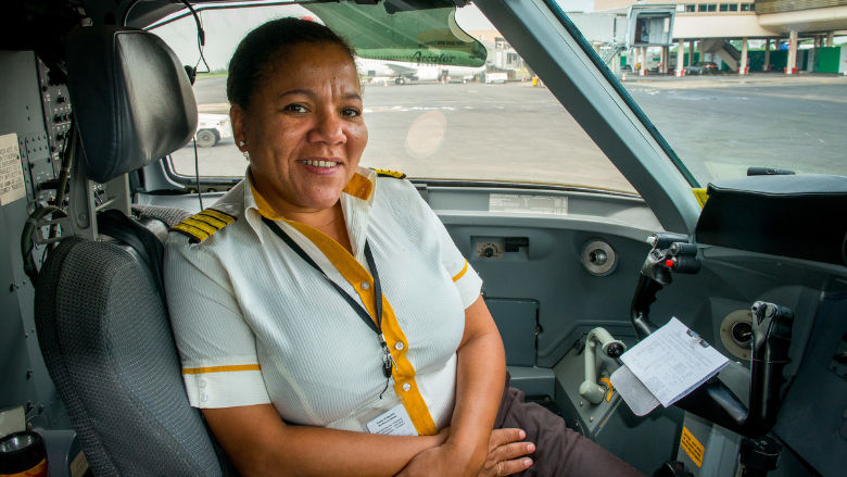 Professional female pilot in aircraft cockpit before takeoff.