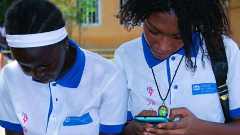 Two female grade school children in Bissau Guinea Bissau use their cellphones to check their homework after school