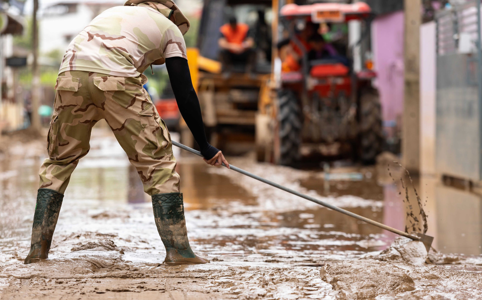 Thai workers cleaning a mud-covered street after a major flood