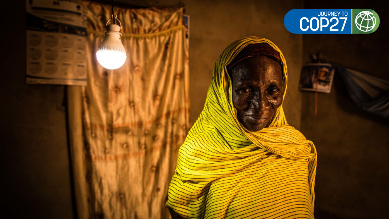 50-year old Aicha Diouf at her home in Senegal, standing by a ceiling light. She got electricity at home recently.