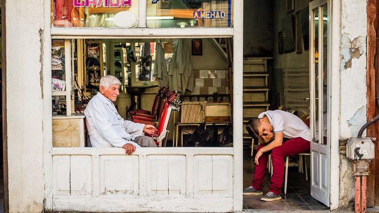 An elderly man and a young boy are sitting in a barbershop in Skopje's Old Bazaar