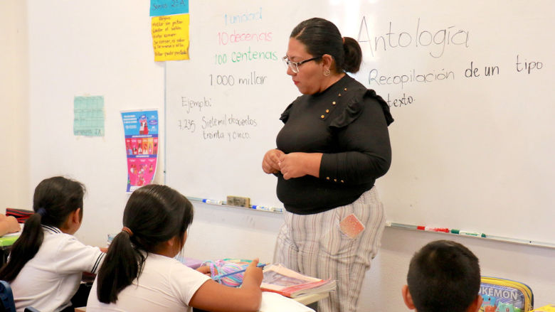 Maestra con alumnos en aula de clase 