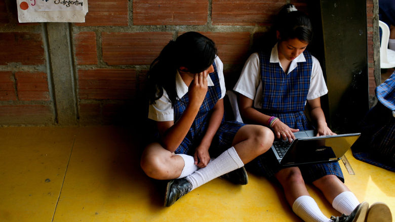 Niña usando una laptop en el pasillo de su escuela 