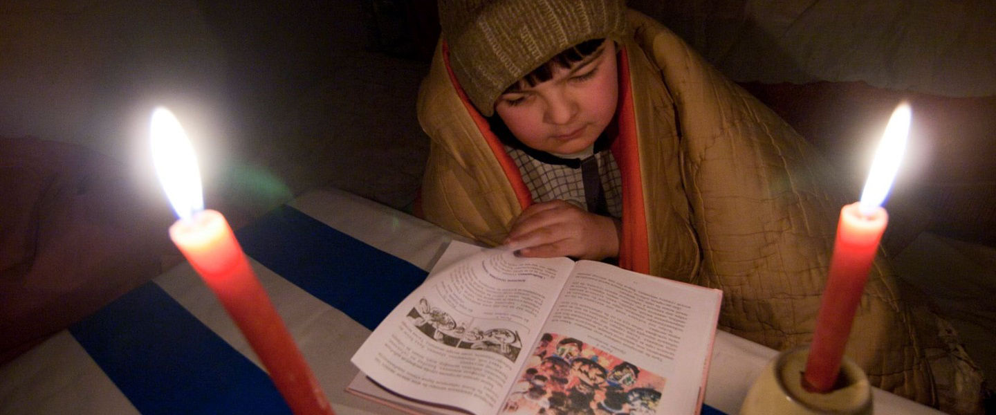 A boy reading by candlelight in a village in Tajikistan