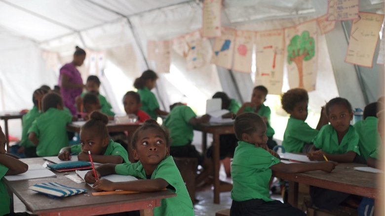 In Vanuatu, primary school students attend lessons in temporary tents as their classrooms remain unsafe. 