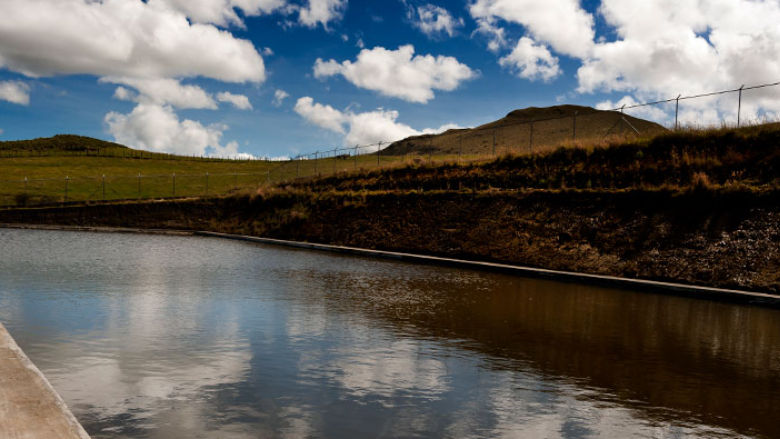 Embalse de agua retenido en una presa donde se cuida del líquido elemento. Paisaje con cielo azul y nubes en Pifo, Ecuador.