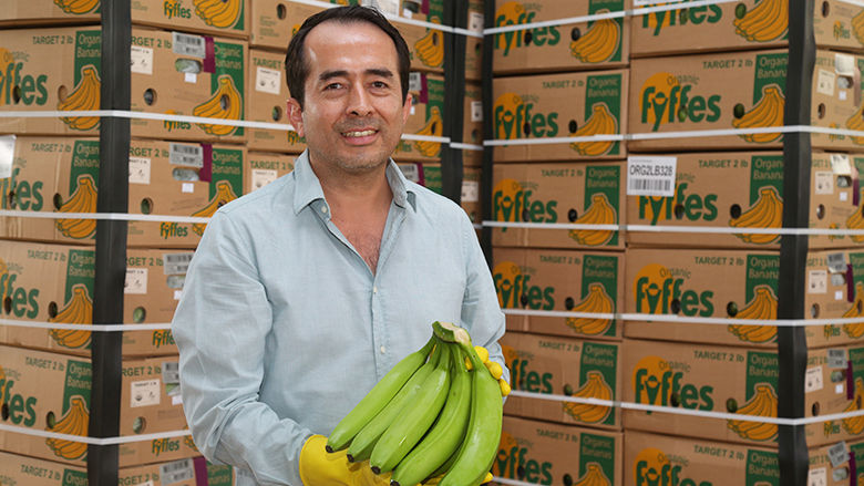 Darwin Pineda posando con bananas de la producción de la empresa Deli Banana.