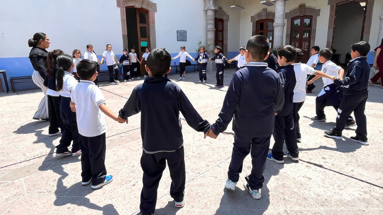 Niños juegan con su maestra en el patio de su escuela 
