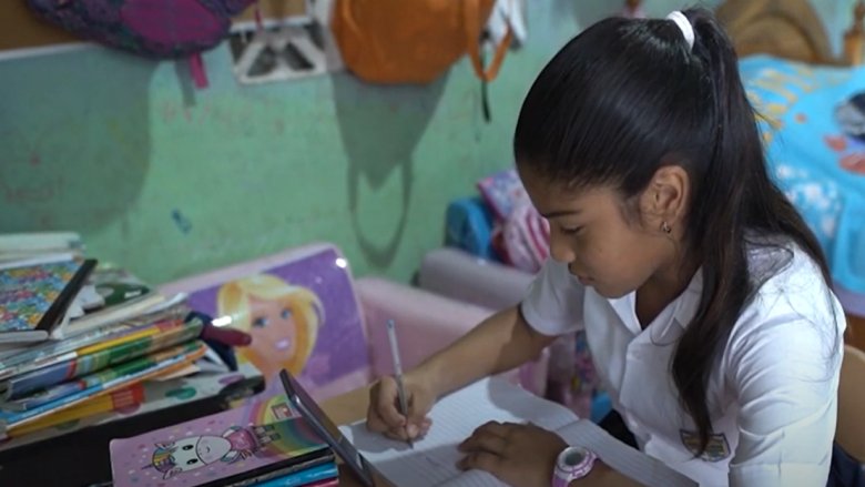 Génesis, niña panameña de 11 años, estudiando en su casa con apoyo de un teléfono celular.  