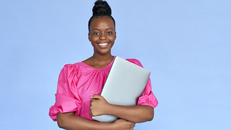A young African girl holding a laptop is determined to  be an innovator and creator of digital technologies