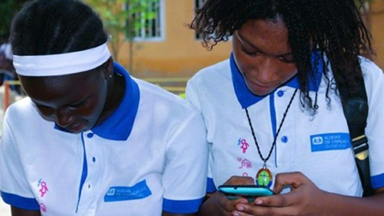 Two female grade school children in Bissau Guinea Bissau use their cellphones to check their homework after school
