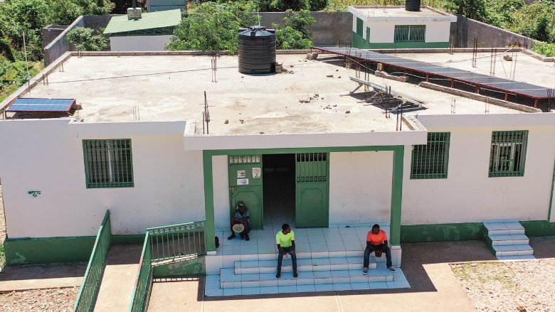 Image showing two men sitting outside of a healthcare facility in Haiti.