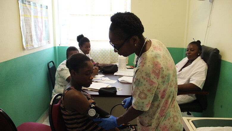 Una enfermera mide la presión arterial de una adolescente embarazada 