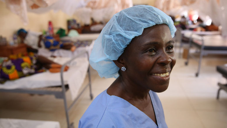 A woman health worker is smiling at the camera inside a hospital guard.