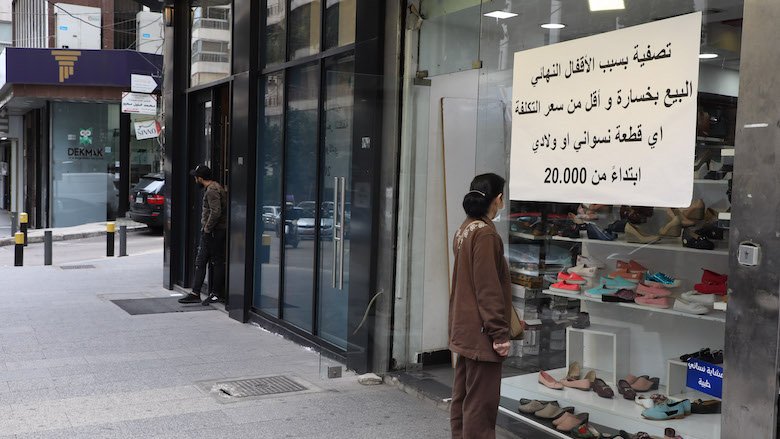A women reads a sign in front of a shop in Lebanon.