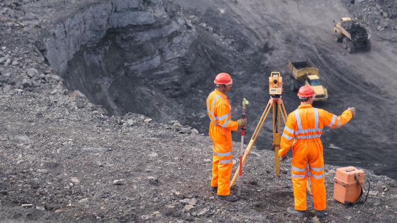 Two men in orange clothing survey a large site