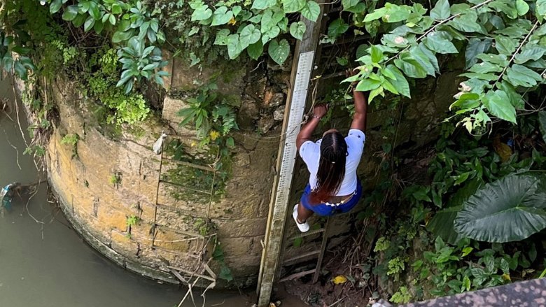 Kerry-Ann, a Jamaican woman whose vigilance helps communities in Central Jamaica avert disaster, scales a ladder.