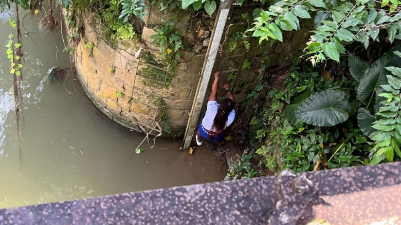 Kerry-Ann, a Jamaican woman whose vigilance helps communities in Central Jamaica avert disaster, scales a ladder.
