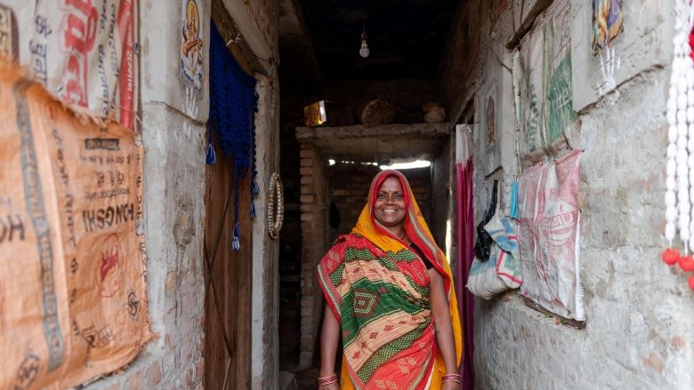 A woman from Nepal stands on a corridor and smiles 