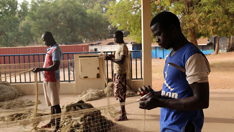 A fisherman fixes a fishing net in Bissau, Guinea. (World Bank/ Madjiguene Seck) 