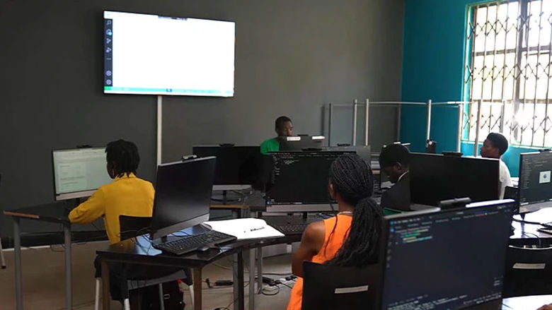 People using desktop computers in a classroom training setting, learning coding and digital skills in a computer lab environm