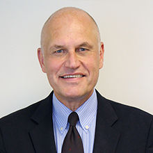 Male wearing dark blue suit and power blue blouse with dark tie