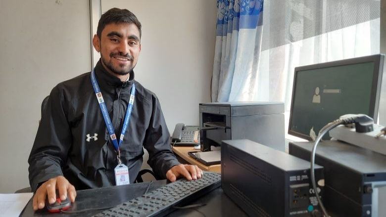 A man smiles from his work desk