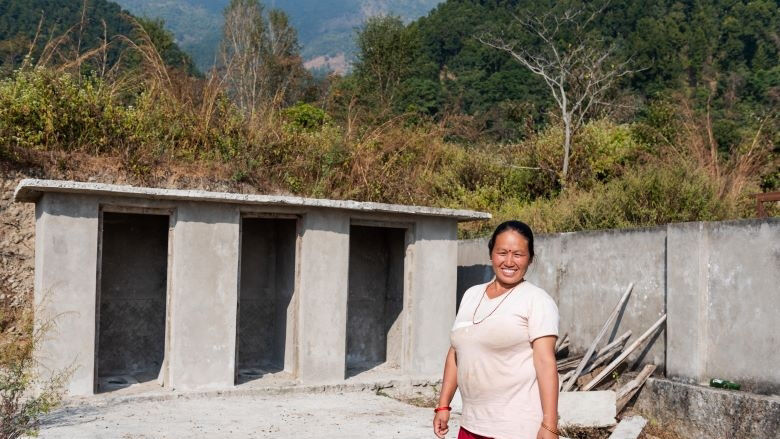 A woman stands in front of a newly constructed toilet 