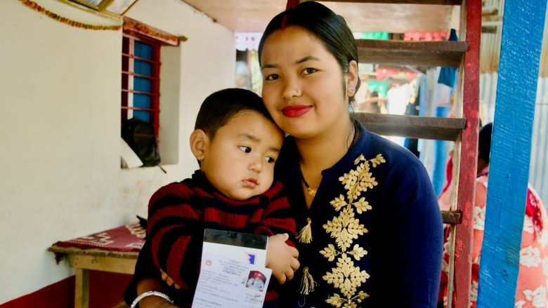 A mother from Nepal holds her child and smiles