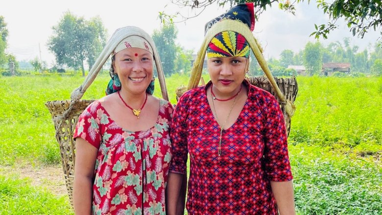 Two women stand in a field wearing red patterned dresses.