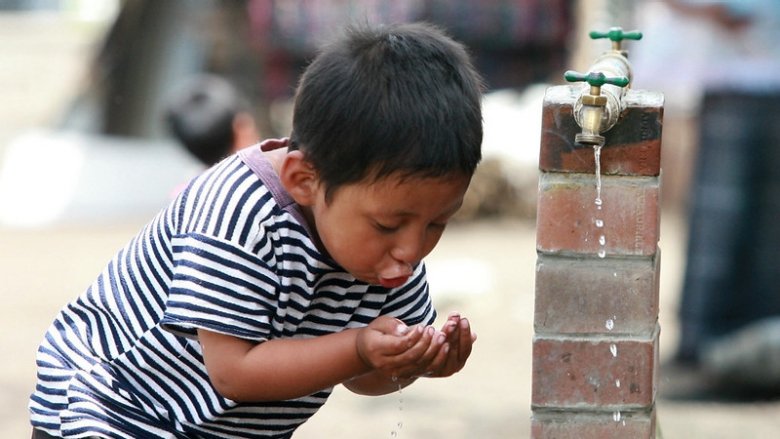 Niño bebiendo agua de un grifo público en Guatemala 
