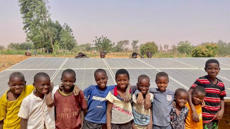 Group of smiley children in front of solar panels in Niger.