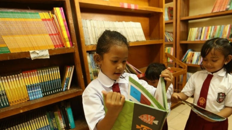 Three young Indonesian girls reading books in their school library. Copyright: Achmad/World Bank