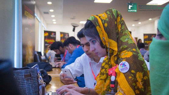 Young woman working on her laptop next to people working beside her.