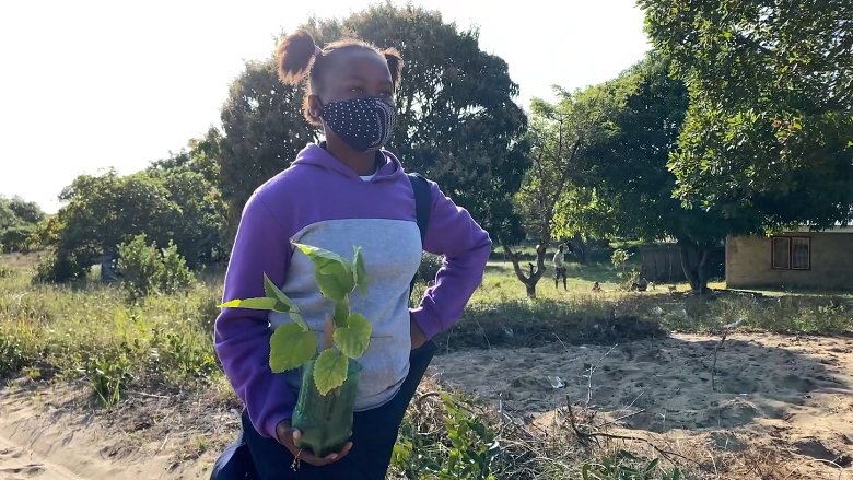 Girl wearing a face mask carrying a plant in her hands while walking outdoors