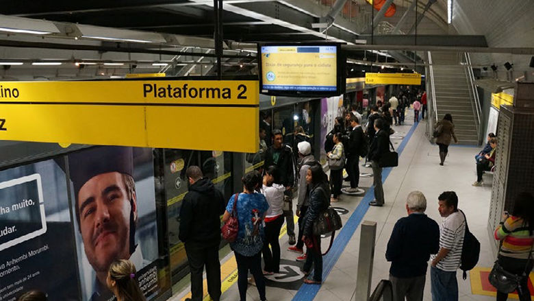 Crowded São Paulo Metro platform as commuters line up to board a train at Plataforma 2 during peak hour.