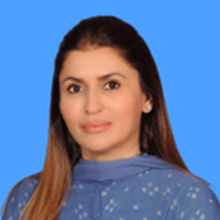 Female with long brown hair wearing a blue patterned top