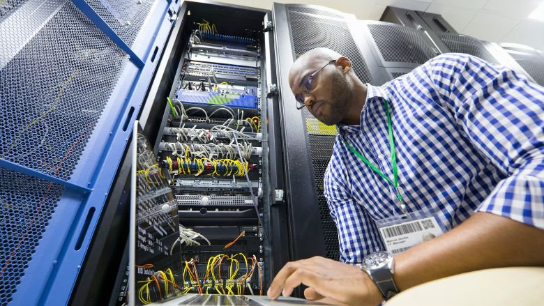 Technician with a laptop checking server in a data center