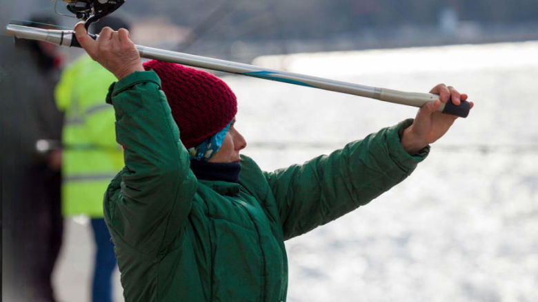 Female fisher casting a line near the shore, illustrating livelihoods.