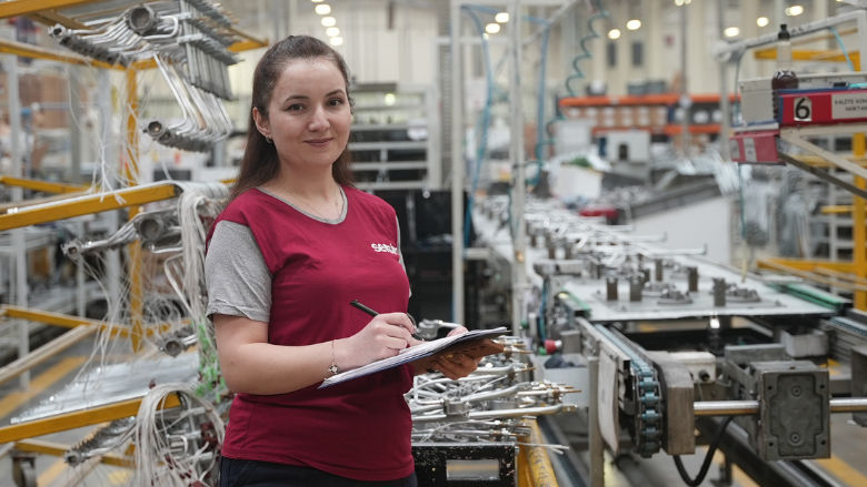 Cangül, a quality control checker at Turkish appliance manufacturer Sersim, standing next to the production line