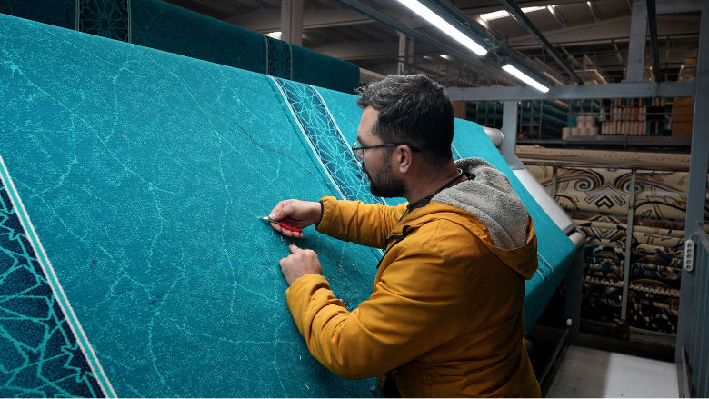 A young man works on a turquoise-colored carpet design at Arya Halı, a carpet producer and exporter located in Gaziantep