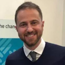 Male wearing white blouse under a blue pullover