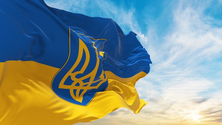 A flag featuring Ukraine's trident emblem against a blue sky