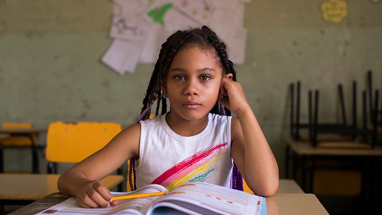 Una niña con un libro de estudios en la Escuela Salomé Ureña 780x439