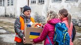 Volunteer handing box of food donations to displaced Ukrainians