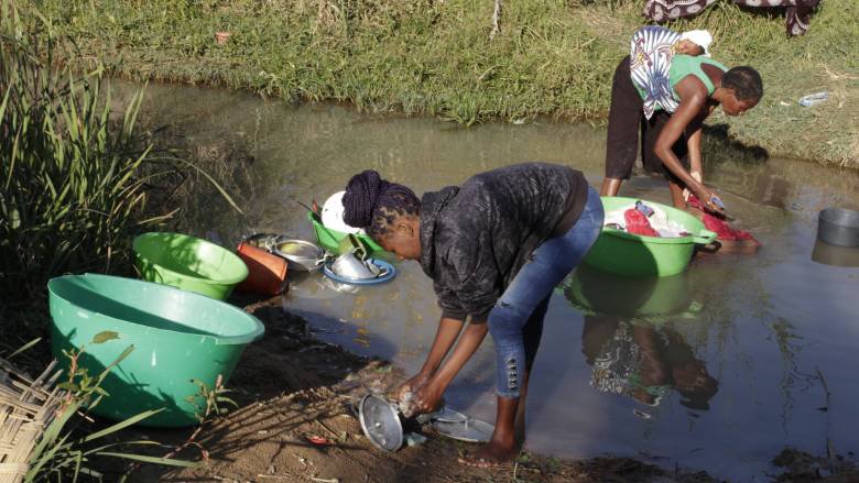 Women washing dishes in a stream in Angola.